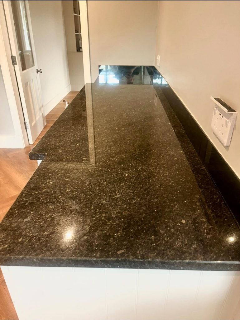 Long dark granite bar top restored to a mirror finish, reflecting the room behind it