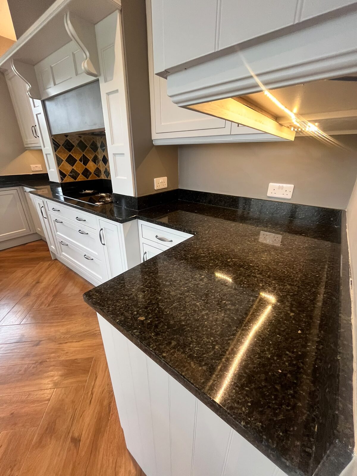 Dark granite kitchen worktops and upstands restored to an even gloss finish